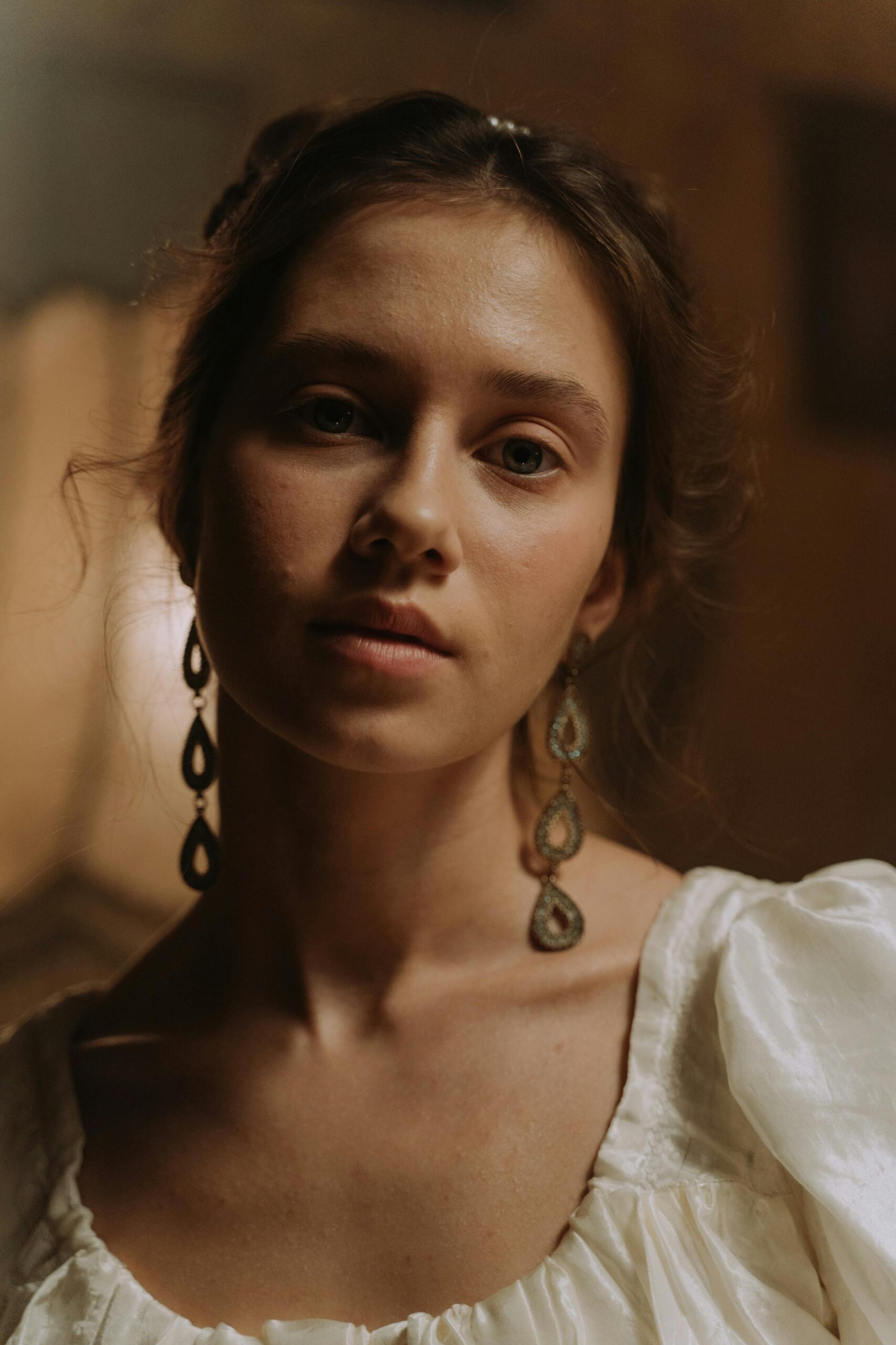 Portrait of a woman in 19th century-inspired attire with elegant earrings, exuding timeless beauty.